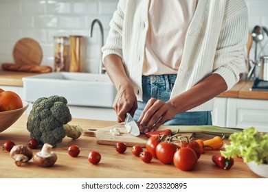 Close-up of unrecognizable woman cutting vegetables at the domestic kitchen - Shutterstock ID 2203320895