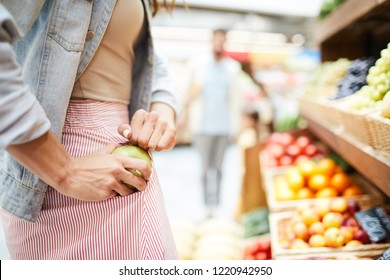 Close-up Of Unrecognizable Woman In Stripped Skirt Hiding Apple In Pocket While Stealing It In Food Store