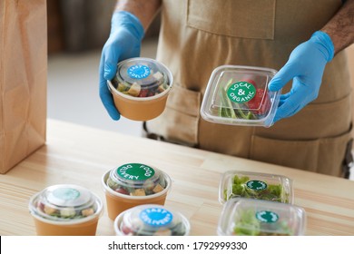 Closeup Of Unrecognizable Worker Wearing Protective Gloves Safely Packaging Orders At Wooden Table In Food Delivery Service, Copy Space