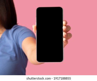 Closeup Of Unrecognizable Young Woman Holding Mobile Phone With Black Blank Screen In Hand, Showing Device To Camera. Gadget With Empty Free Space For Mock Up Template, Selective Focus