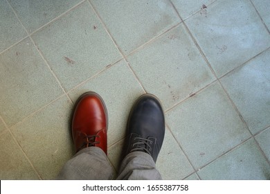 Closeup Upper Of Mismatched Shoes, A Man Wearing Two Different Shoes And Different Colors Standing On Tiled Floor, Break The Rules, Revolution Metaphor 