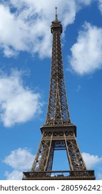 Close-up of the upper part of the Eiffel Tower against a cloudy sky