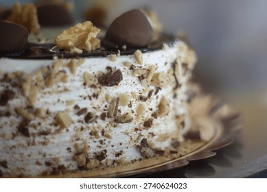 Close-up of the cake’s upper side featuring chocolate glaze, walnut pieces, and chocolate halves arranged on top.