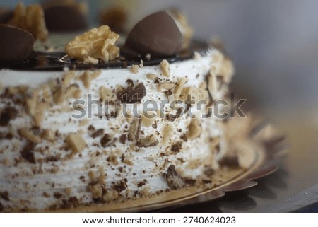 Close-up of the cake’s upper side featuring chocolate glaze, walnut pieces, and chocolate halves arranged on top.