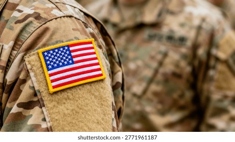 Close-up of a US flag patch on a camouflage military uniform sleeve with yellow border, blue field of white stars, and red and white stripes