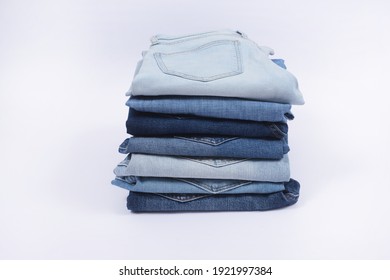 Closeup Lot of used different jeans stacked in a pile isolated on white background

