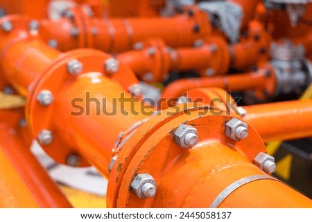 Close-up of used flanges and welded pipes starting to rust with heavy metal fitting bolts on pipes that transport fluids to oil and gas rigs.