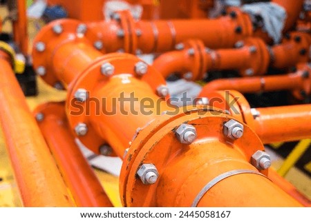 Close-up of used flanges and welded pipes starting to rust with heavy metal fitting bolts on pipes that transport fluids to oil and gas rigs.