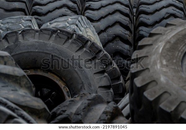 Closeup used truck tires. Old tyres waste for\
recycle or for landfill. Black rubber tire of truck. Pile of used\
tires at recycling yard. Material for landfill. Recycled tires.\
disposal waste tires.