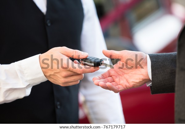 Close-up\
Of Valet\'s Hand Giving Car Key To\
Businessperson