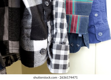 Close-up of various plaid and solid shirt sleeves hanging in wardrobe. Colorful buttoned shirt cuffs, flannel and cotton fabrics in casual fashion style. Closet storage and menswear concept