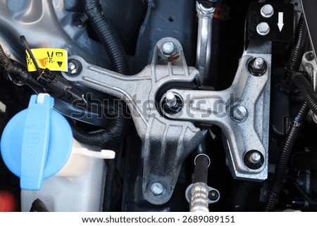 Close-up of vehicles top engine mount showing metal components, bolts, and wiring under hood of electric vehicle. Engine mount new car. Engine parts under the hood of the car.