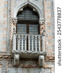 Close-up of a Venetian balcony with intricate stone carvings and lion head sculptures, showcasing traditional Italian Gothic architecture in Venice, Italy.