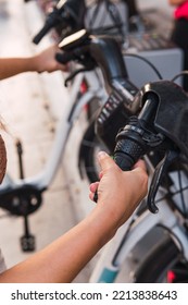 Close-up Vertical Image Of An Unrecognizable Woman's Hands Pulling A Rental Bike Out Of Its Parking Spot In The Big City Of Madrid.