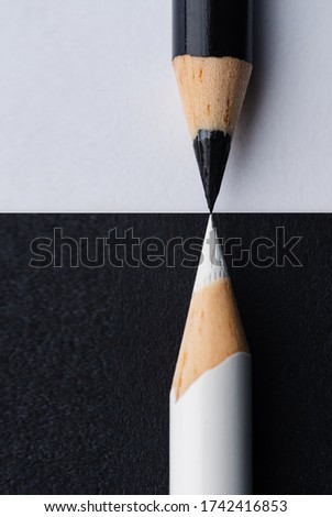 A closeup vertical shot of black and white pencils on black and white backgrounds- perfect for contrast, connection concepts