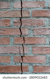  Close-up of a vertical structural crack running through a weathered red brick wall