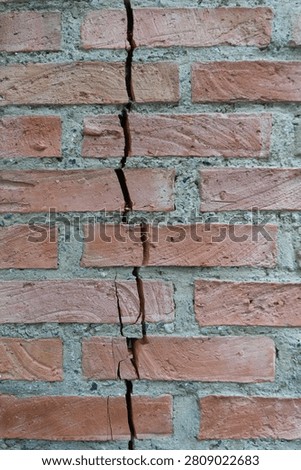 Close-up of a vertical structural crack running through a weathered red brick wall
