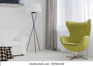 Close-up of a very bright room corner with a unique floor lamp and a swivel egg chair