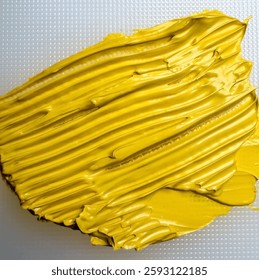 A close-up of a vibrant yellow oil paint smear on a white surface. High quality photo