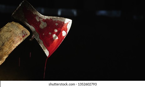 Closeup Video: Axe With Blood In Hand On The Dark Background. Drops Of Blood Flow Down The Blade Of An Ax. Murderer Or Butcher, Halloween Theme