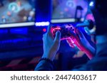 Close-up, video game console controller in gamer hands at colorful neon light living room at night, E-sport streaming game online, selective focus