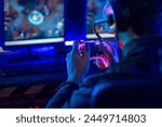 Close-up, video game console controller in gamer hands at colorful neon light living room at night, E-sport streaming game online, selective focus
