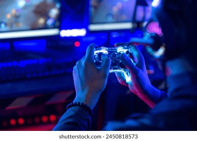 Close-up, video game console controller in gamer hands at colorful neon light living room at night, E-sport streaming game online, selective focus - Powered by Shutterstock