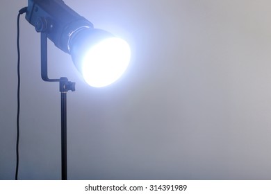 Closeup Video Light Shines Standing On Black Tripod In Grey Studio