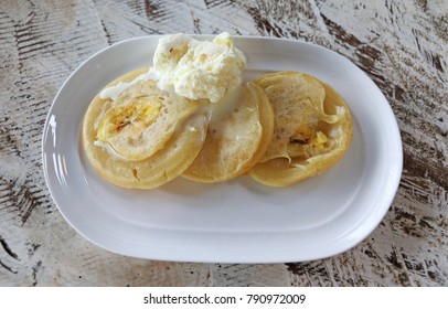 Close-up View Of 3 Delicious Mini Banana Pancakes With A Scoop Of Vanilla Ice-cream In A White Plate On A Wooden Table