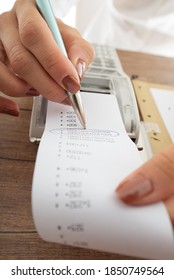 Closeup View Of An Accountant Checking Receipt Coming Out Of An Adding Machine.