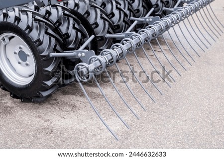 Close-up view of agricultural machinery focusing on metal tines and tire tread, located on a farm.