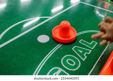 A close-up view of an air hockey game, focusing on the puck and a player's hand. Close-up of a Game in Progress of Air Hockey Action. - Powered by Shutterstock