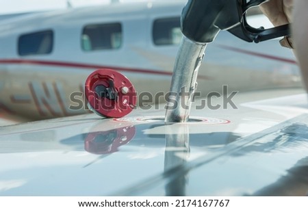 A close-up view of the aircraft's fuel tank, fuel is being filled into the tank. Fuel nozzle filling up aircraft, refueling jet fuel in an aircraft wing. 