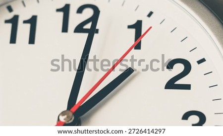 A close-up view of an analog clock face with black hour and minute hands and a red second hand, set against a white background with clear black numbers and markings