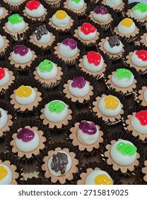 A close-up view of assorted bite-sized dessert tartlets arranged neatly in rows on a tray. Each mini tart features a crisp pastry base filled with smooth white cream