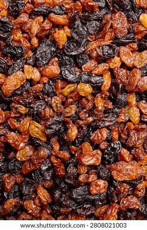 Close-up view of assorted raisins in different colors and sizes, highlighting their wrinkled texture and natural variations on a flat surface