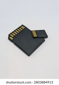 Close-up view of the back side of a black SD memory card and a MicroSD card showing their electronic gold pins, isolated on a white background. Digital storage technology concept.