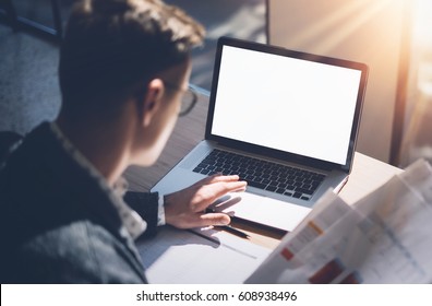 Closeup view of banking finance analyst in eyeglasses working at sunny office on laptop while sitting at wooden table.Businessman analyze stock report on notebook screen.Blurred,horizontal mockup