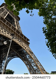 Close-up view of the base of the Eiffel Tower while walking in the Champ de Mars in Paris, France