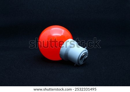 Close-up view from base of a zero watt bulb orange colored on a black background