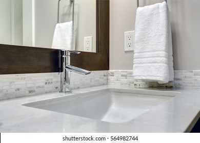 Close-up View Of Bathroom Vanity Cabinet Topped With White And Grey Counter Paired With Tile Backsplash Under Framed Mirror. Northwest, USA
Northwest, USA
