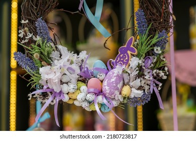 Close-up view of beautiful Easter wreath hangs in store during the holiday.Wreath made from artificial eggs, flowers, tree branches and rabbit shaped decoration. Easter decoration theme.