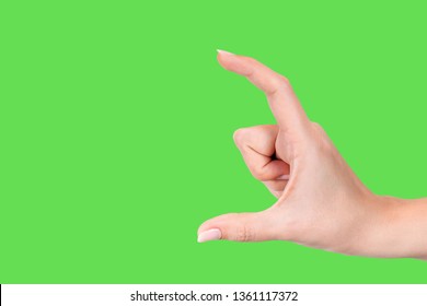 Closeup view of beautiful white female hand making gesture as if holding something virtual and invisible between her two fingers. Fingernails with pastel pink manicure. Isolated og green background. - Powered by Shutterstock