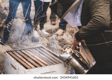 Close-up view of a beekeeper using a smoker to calm bees during hive maintenance - Powered by Shutterstock