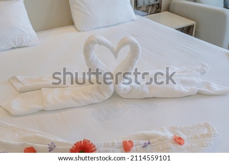 Closeup view of big bed decorated with cute swans made of white towels in hotel room
