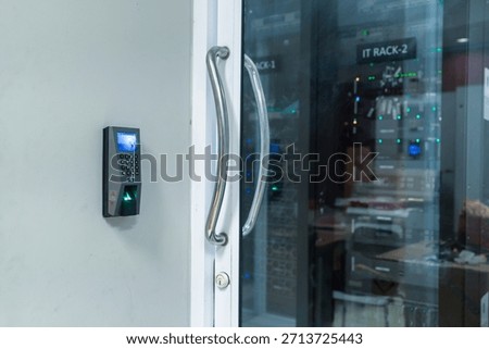 A close-up view of a biometric access control system installed on a modern glass door in an office setting. Features advanced fingerprint technology for security.