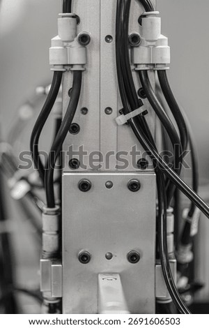 Close-up view of black cables connected to a metallic industrial machine component with bolts and zip ties, showcasing technical detail and precision. Includes copy space