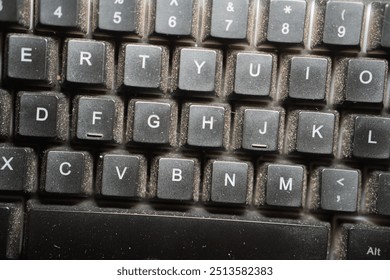 Close-up view of a black computer keyboard with various function keys and alphanumeric keys. The keyboard shows signs of dust accumulation.