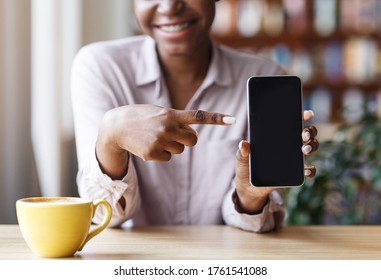 Closeup View Of Black Girl Pointing At Empty Mobile Phone Screen With Space For Your Design At City Cafe