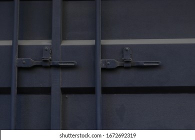 Close-up View Of Black Metal Latch Shipping Container Doors, The Locked Door Handles Of A Black Shipping Container.